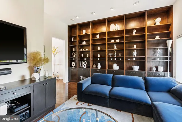 a living room with furniture a flat screen tv and floor to ceiling window