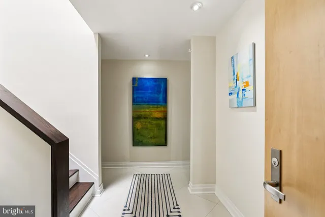 a view of a hallway with wooden floor and a bathroom