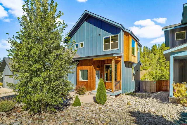 a view of a blue house with large windows and plants