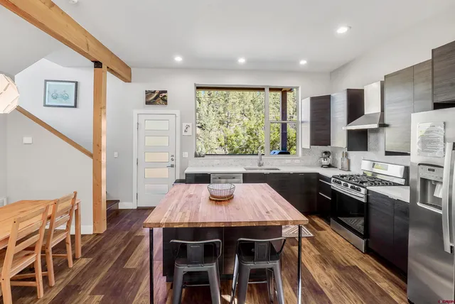 a kitchen with stainless steel appliances granite countertop a kitchen island hardwood floor sink stove dining table and chairs