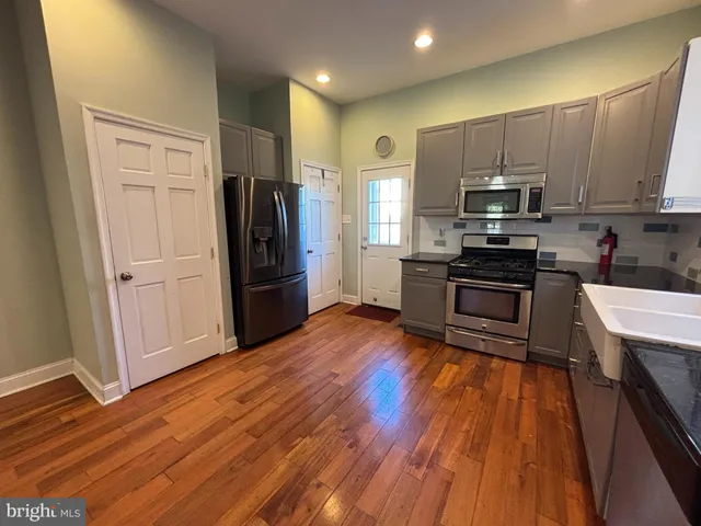 a kitchen with stainless steel appliances a refrigerator stove and wooden floor