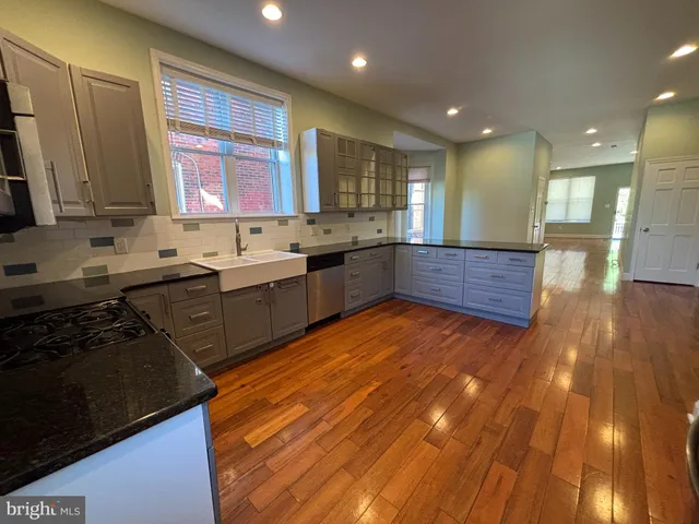 a large kitchen with a sink and wooden floor