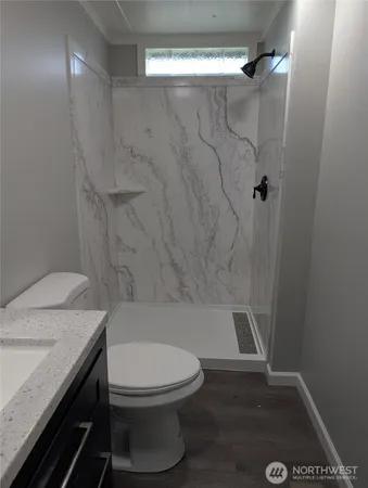 a bathroom with a granite countertop bathtub shower sink vanity and toilet