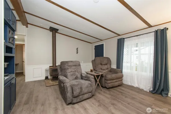 a living room with couches and a flat screen tv with kitchen view