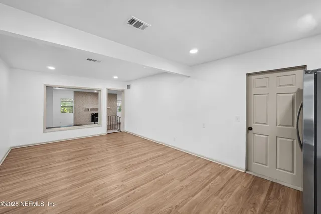 a view of empty room with wooden floor and window