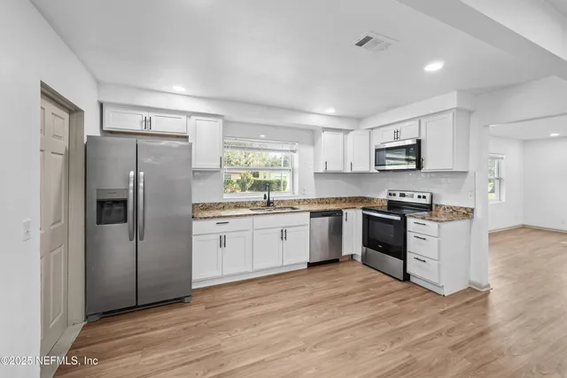 a kitchen with granite countertop a refrigerator stove top oven and sink