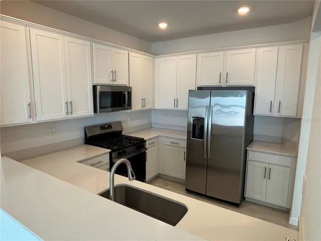 a kitchen with a refrigerator sink and cabinets