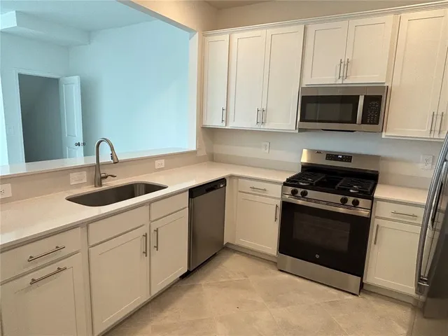 a kitchen with white cabinets stainless steel appliances and sink