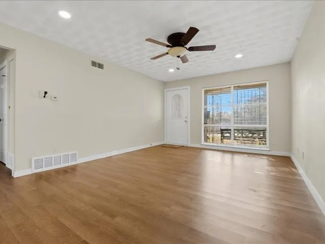 a view of an empty room with a window and wooden floor