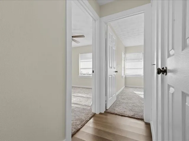 a view of a hallway with wooden floor and a bathroom