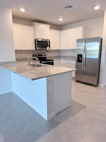 a kitchen with stainless steel appliances granite countertop a refrigerator a stove a sink a microwave and white cabinets