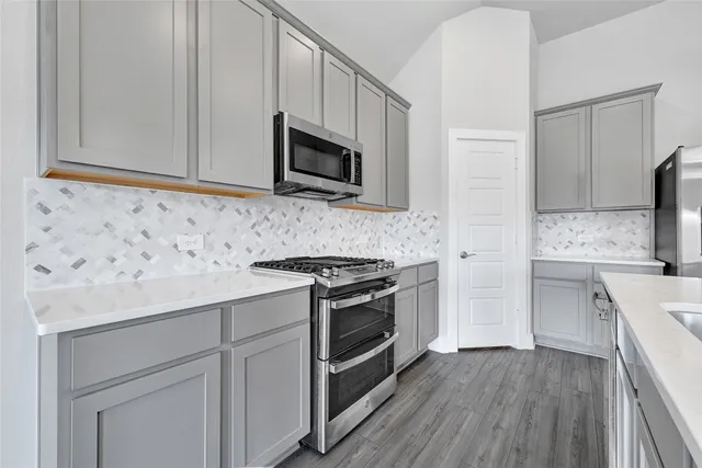 a kitchen with stainless steel appliances white cabinets and a stove top oven