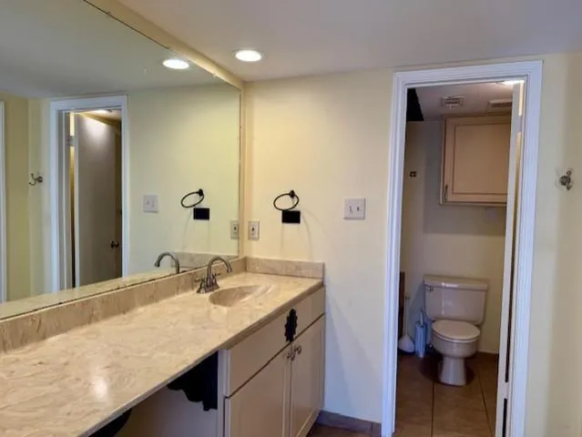 a bathroom with a granite countertop sink a toilet and a mirror