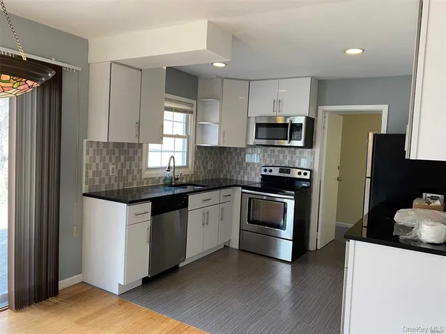 a kitchen with granite countertop a refrigerator and a stove top oven