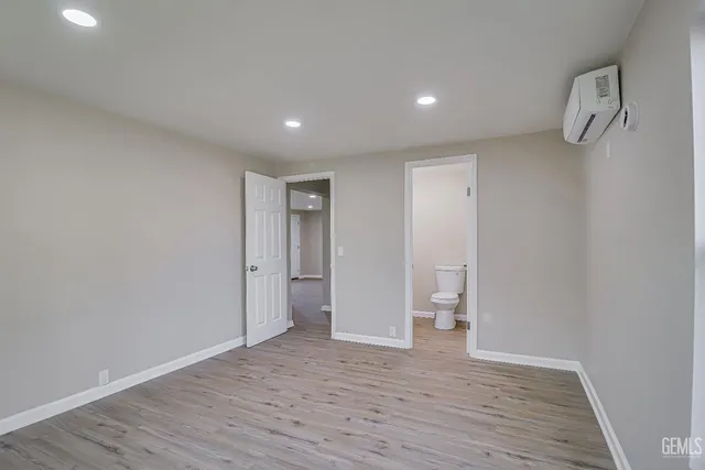 a view of an empty room with wooden floor and a toilet