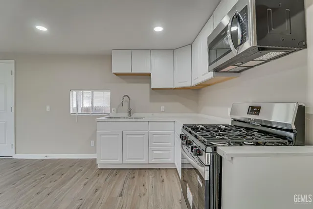 a kitchen with stainless steel appliances granite countertop a sink a stove a microwave and cabinets