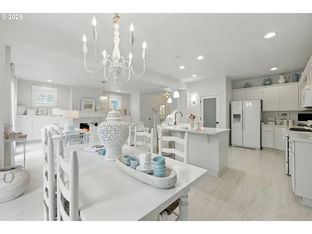 a kitchen with stainless steel appliances kitchen island granite countertop a refrigerator a stove a sink dishwasher and white cabinets with wooden floor