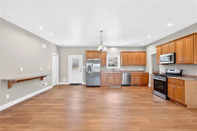 a large white kitchen with stainless steel appliances granite countertop a stove and a sink
