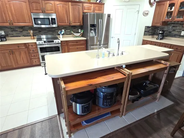 a kitchen with kitchen island a stove a microwave a sink and cabinets