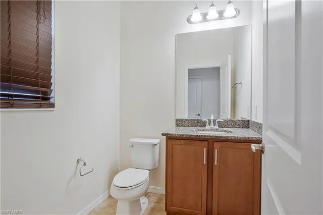 a bathroom with a granite countertop toilet a sink and mirror