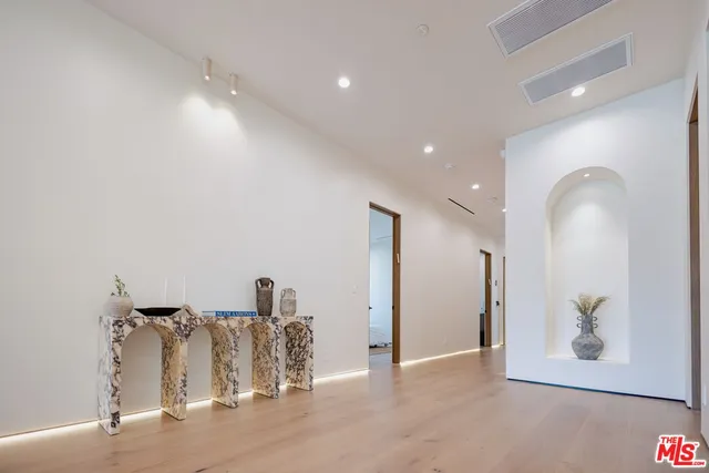 a living room with stainless steel appliances furniture a flat screen tv and a kitchen view