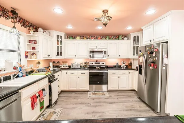 a kitchen with stainless steel appliances kitchen island granite countertop a refrigerator and a stove top oven