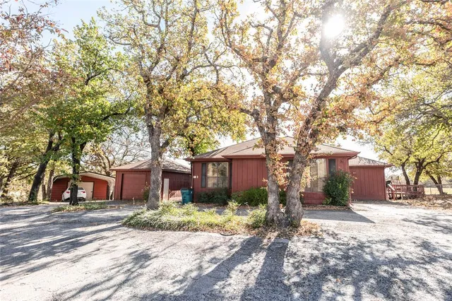 a front view of a house with garden and trees