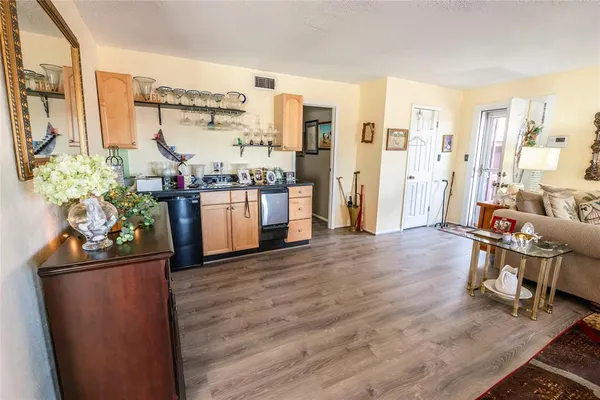 a living room with stainless steel appliances furniture and a wooden floor