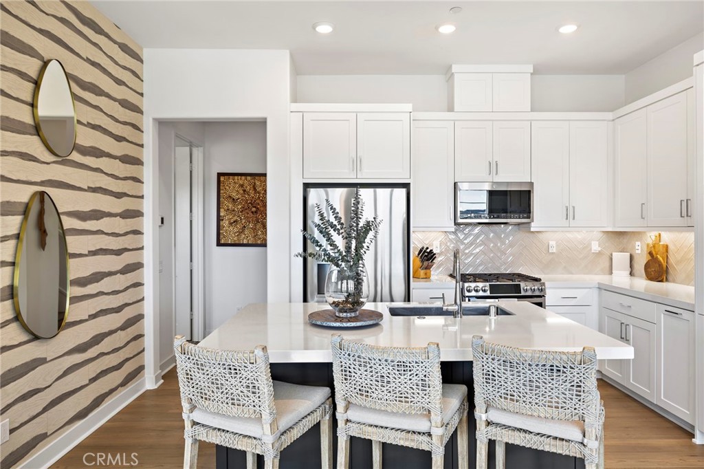 896 Sunrise Road Rancho Mission Viejo, CA 92694 - Photo 17 of 42 a kitchen with stainless steel appliances granite countertop a stove a sink a microwave a refrigerator white cabinets and couches with wooden floor