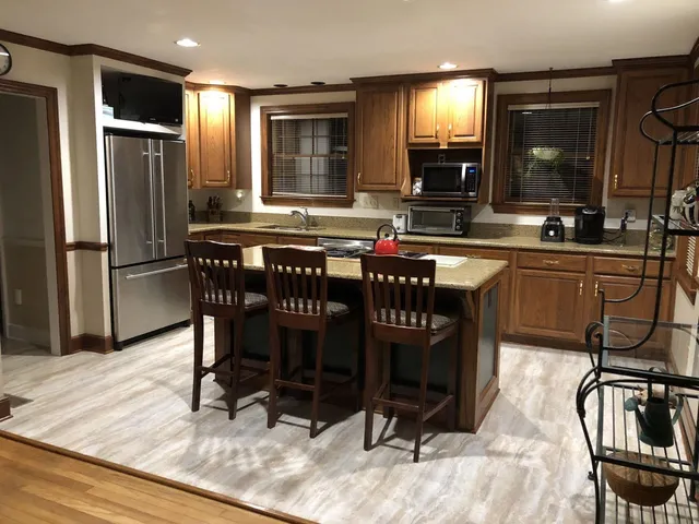 a kitchen with stainless steel appliances granite countertop a sink a stove a dining table and chairs