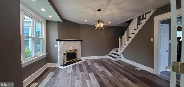 a view of an empty room with wooden floor fireplace and a window