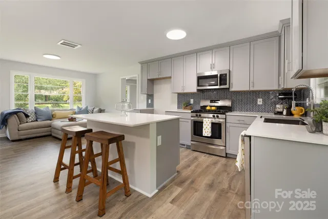 a kitchen with stainless steel appliances kitchen island wooden floors and white cabinets