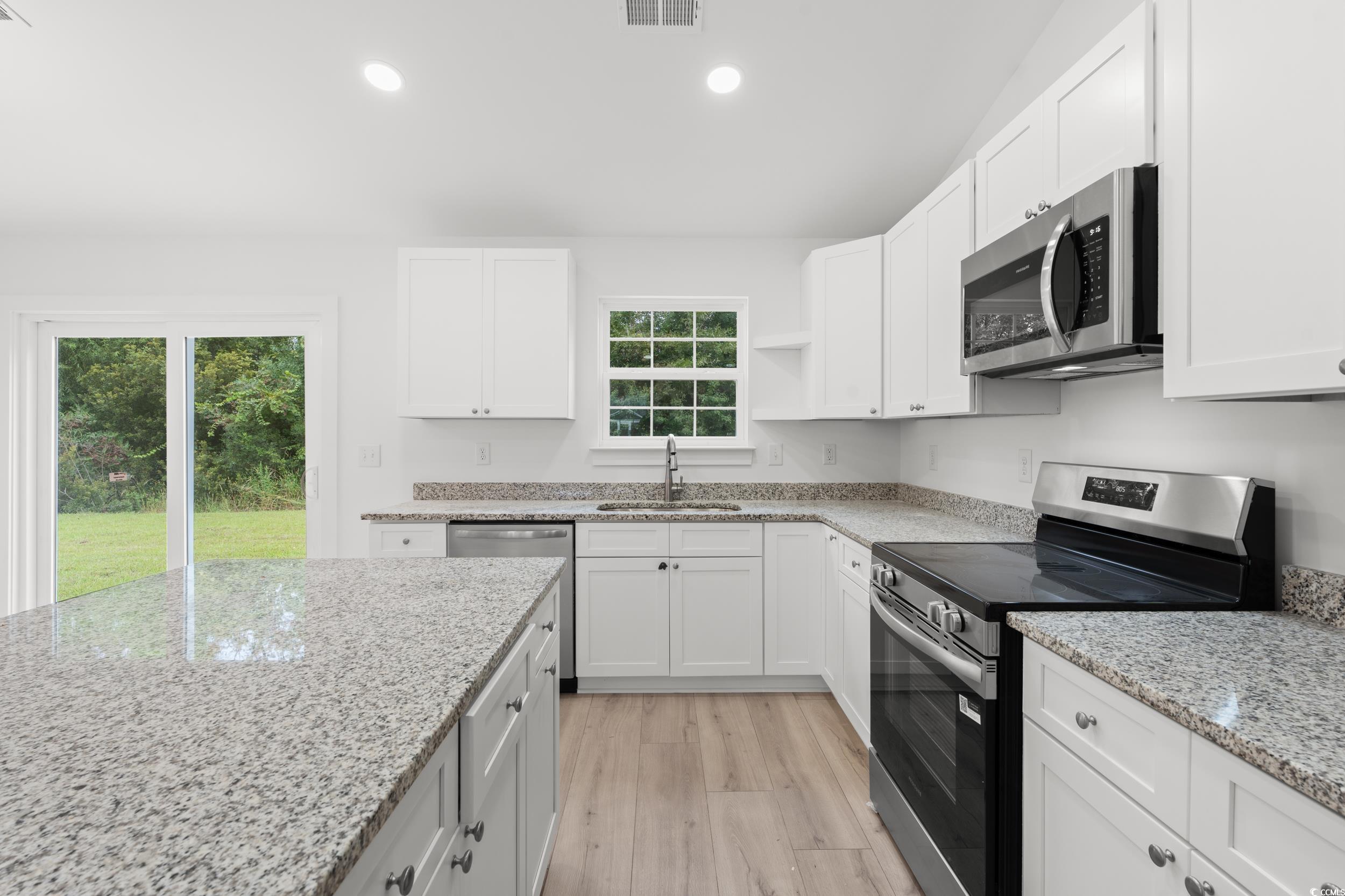 2827 Biscane Court Conway, SC 29527 - Photo 9 of 31 Kitchen with appliances with stainless steel finishes, white cabinetry, light stone counters, recessed lighting, and light wood-style floors