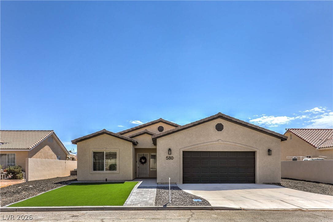 580 Lillian Condie Road Overton, NV 89040 - Photo 3 of 37 An inviting facade with a well-maintained artificial turf lawn and a clean driveway awaits.