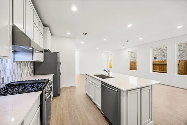 a kitchen with stainless steel appliances granite countertop a sink a stove and a refrigerator
