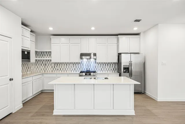 a kitchen with stainless steel appliances kitchen island a refrigerator sink and cabinets
