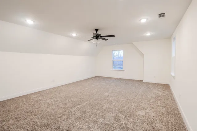 an empty room with a ceiling fan and window
