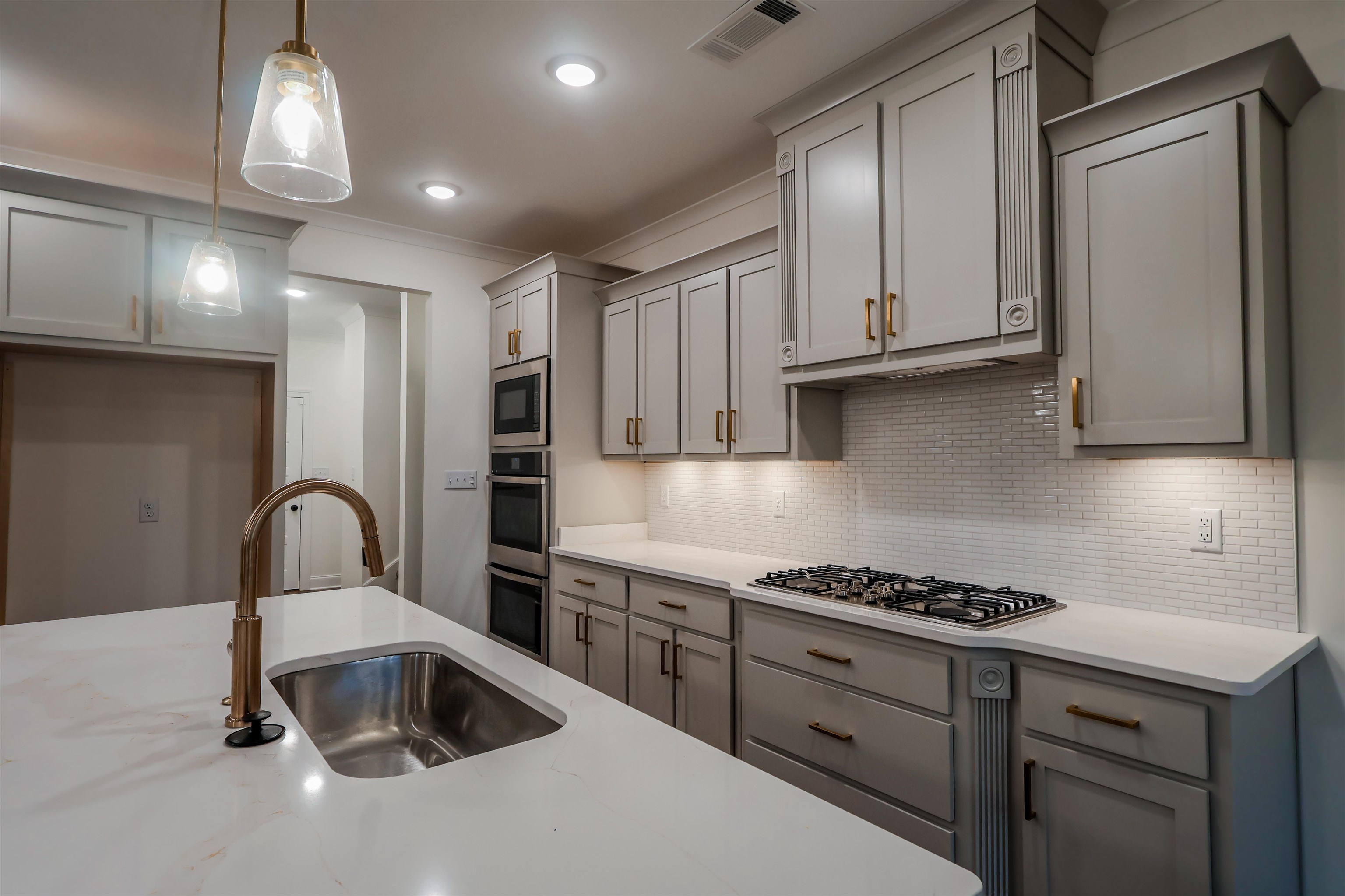 125 Columbia Way Atoka, TN 38004 - Photo 5 of 27 Kitchen with gray cabinetry, pendant lighting, decorative backsplash, ornamental molding, and light stone counters