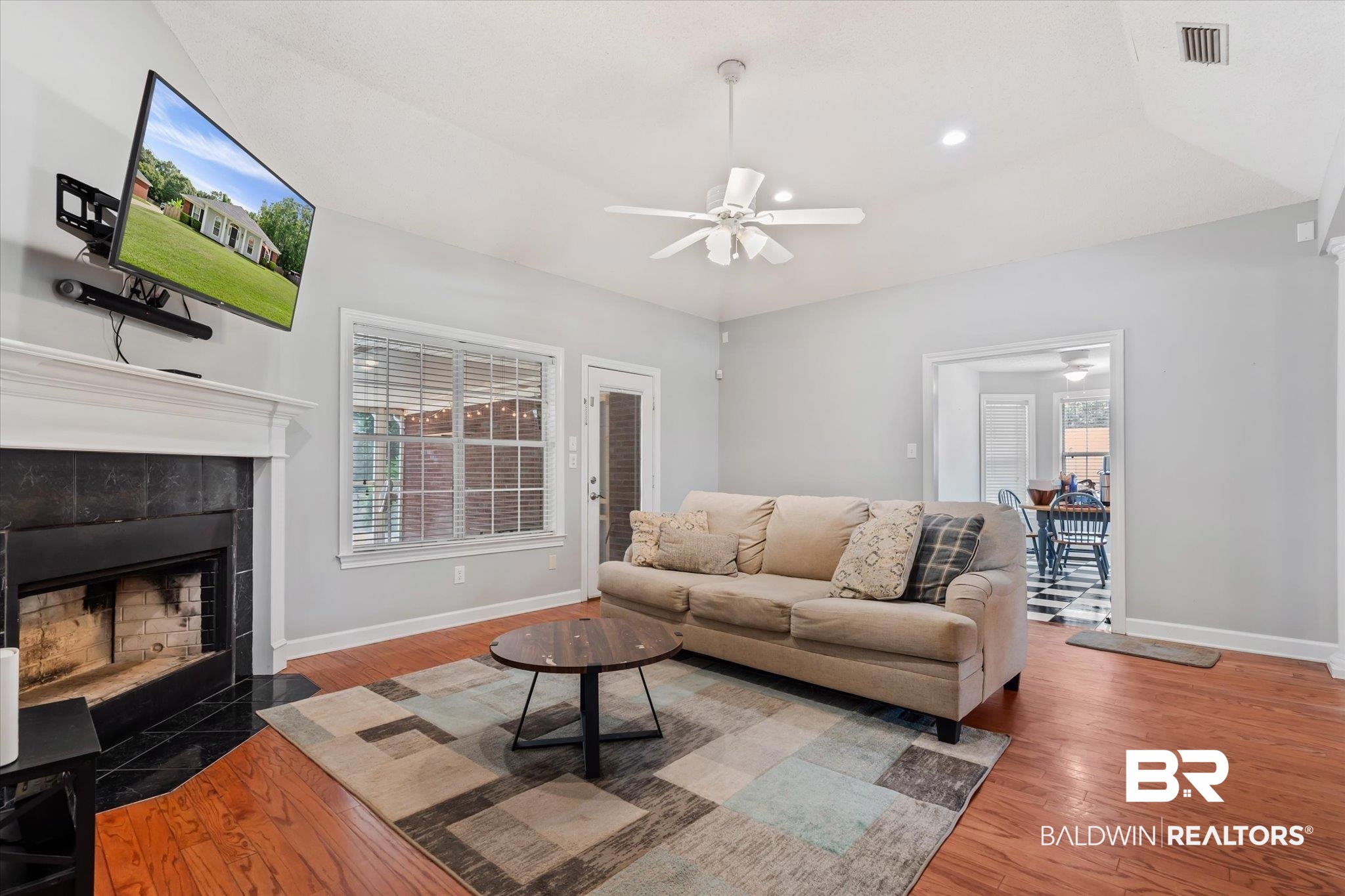 2320 Sequoya Trail Mobile, AL 36695 - Photo 4 of 20 Living room with wood-type flooring, ceiling fan, a raised ceiling, and a tiled fireplace