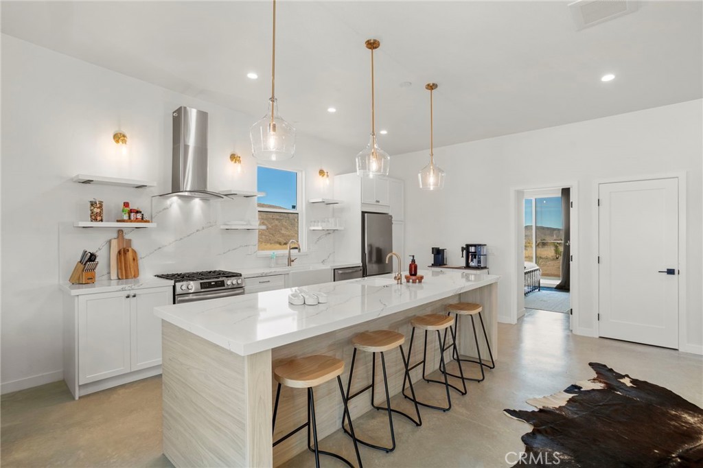 5145 Tom Mix Road Pioneertown, CA 92268 - Photo 19 of 75 a large kitchen with kitchen island a stove a table a sink and a refrigerator