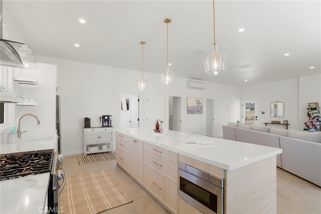 5145 Tom Mix Road Pioneertown, CA 92268 - Photo 20 of 75 a large white kitchen with a large stove a sink a refrigerator and white cabinets with wooden floor