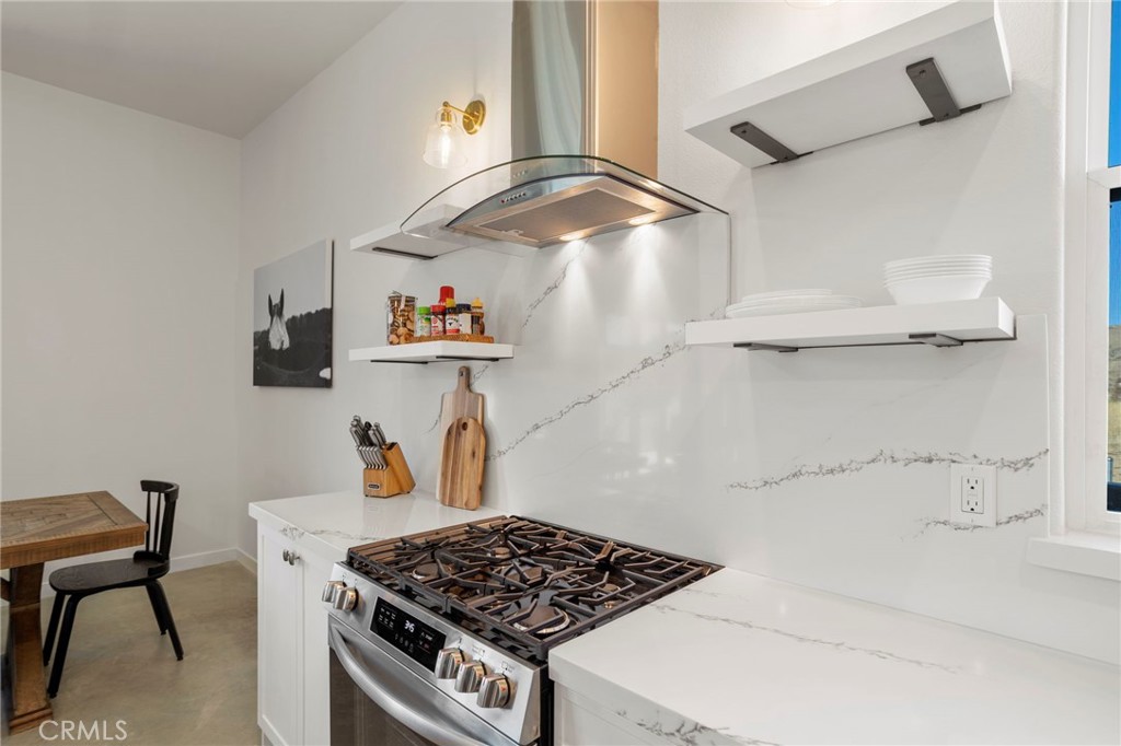 5145 Tom Mix Road Pioneertown, CA 92268 - Photo 21 of 75 a kitchen with stainless steel appliances granite countertop a stove and a wooden floor