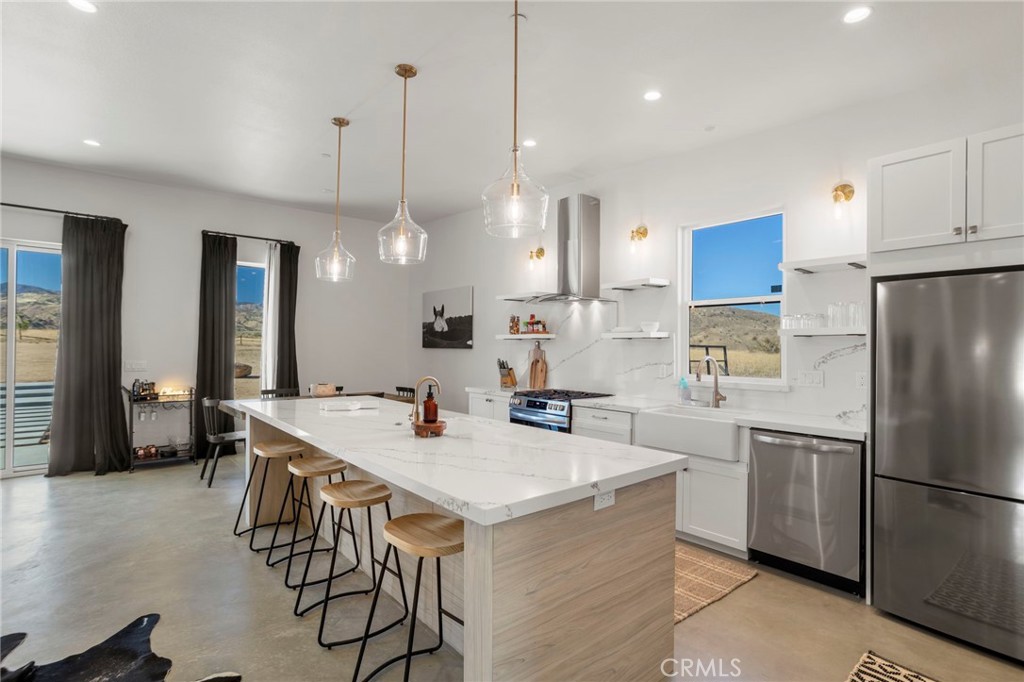 5145 Tom Mix Road Pioneertown, CA 92268 - Photo 24 of 75 a kitchen with stainless steel appliances a stove a sink a refrigerator a center island a dining table and chairs