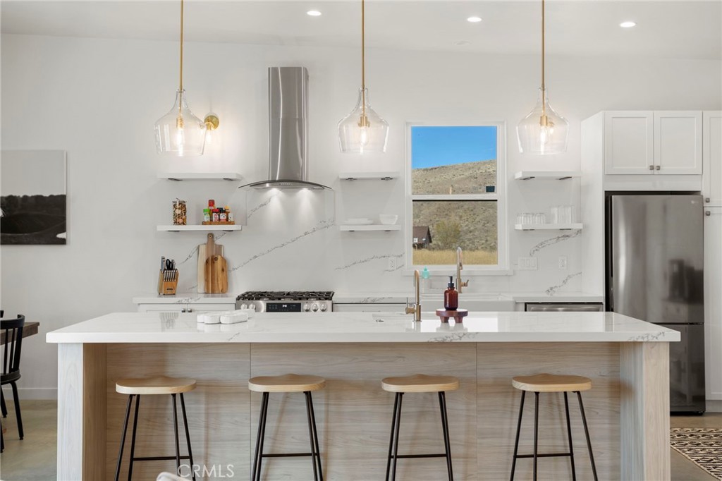 5145 Tom Mix Road Pioneertown, CA 92268 - Photo 26 of 75 a kitchen with stainless steel appliances granite countertop a sink a stove a refrigerator and white cabinets with wooden floor