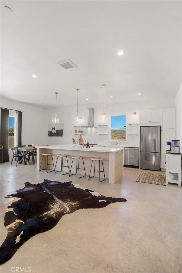 5145 Tom Mix Road Pioneertown, CA 92268 - Photo 27 of 75 a kitchen with stainless steel appliances kitchen island granite countertop a stove a sink a refrigerator and white cabinets