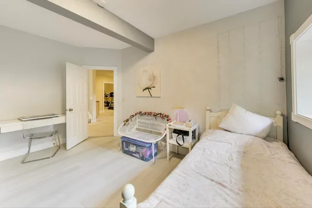 a bedroom with a bed a chair and next to a window