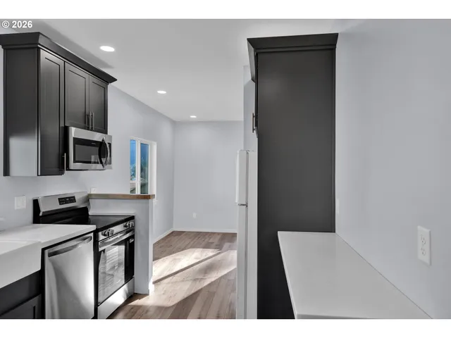 a view of an empty room with wooden floor and windows
