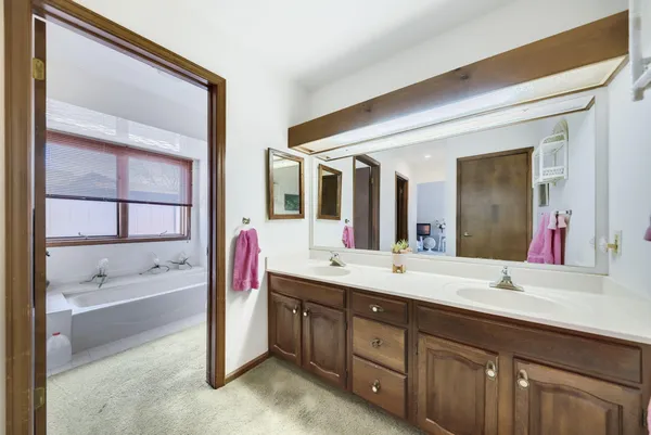 a spacious bathroom with a double vanity sink a large mirror and a bathtub