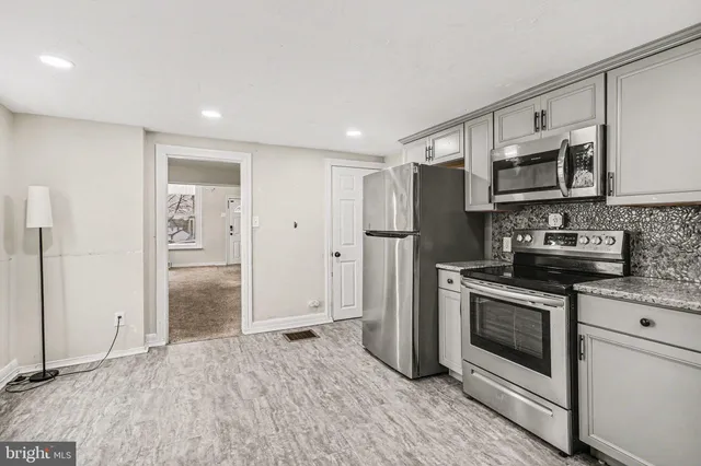 a kitchen with stainless steel appliances granite countertop a refrigerator a stove and a sink