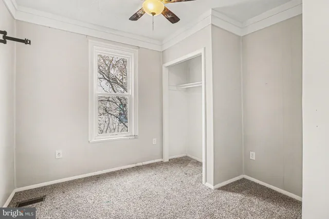 an empty room with windows and fan